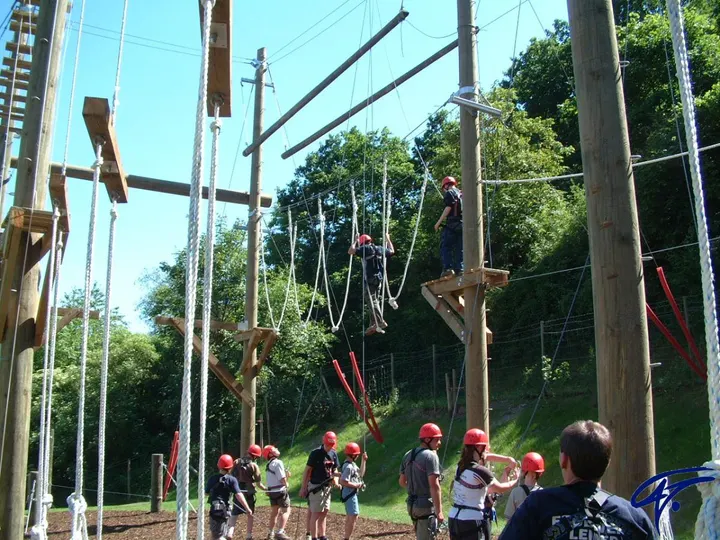 Blick in den Hochseilgarten Bad Neuenahr-Ahrweiler: Holzmasten mit Seilelementen, darunter eine Gruppe mit Helmen