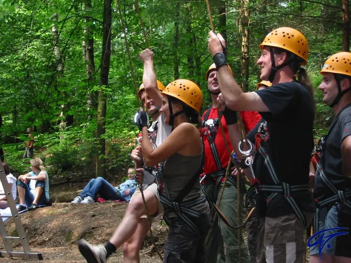 Mehrere Erwachsene mit Helm halten gemeinsam ein Seil und bilden eine Sicherungskette