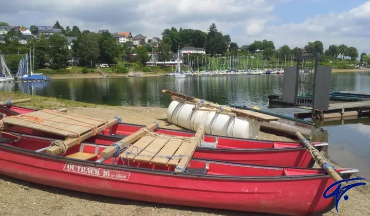 Rote Kanus und Floßmaterial liegen am Ufer des Sorpesees bereit
