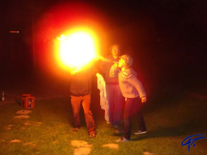 Beim Feuerspucken leuchtet nachts ein großer Feuerball auf, daneben stehen Kinder