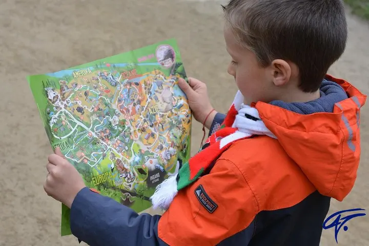 Ein Junge in orangefarbener Jacke studiert eine bunte Karte