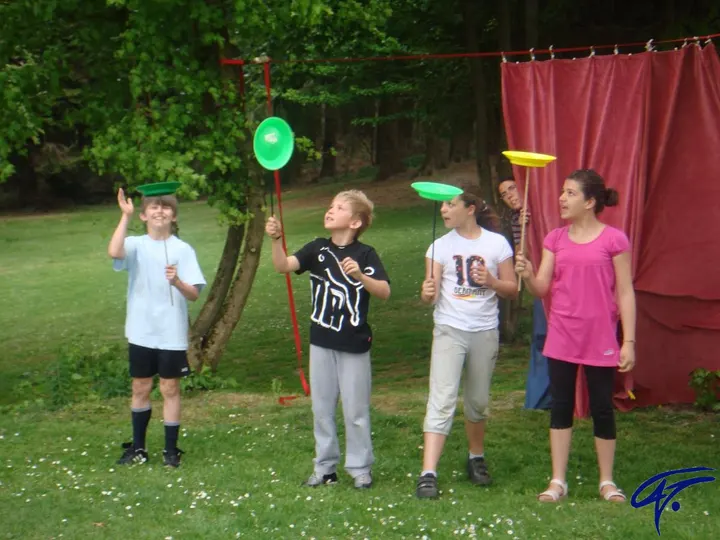 Kinder lassen auf einer Wiese Teller auf Stäben kreisen