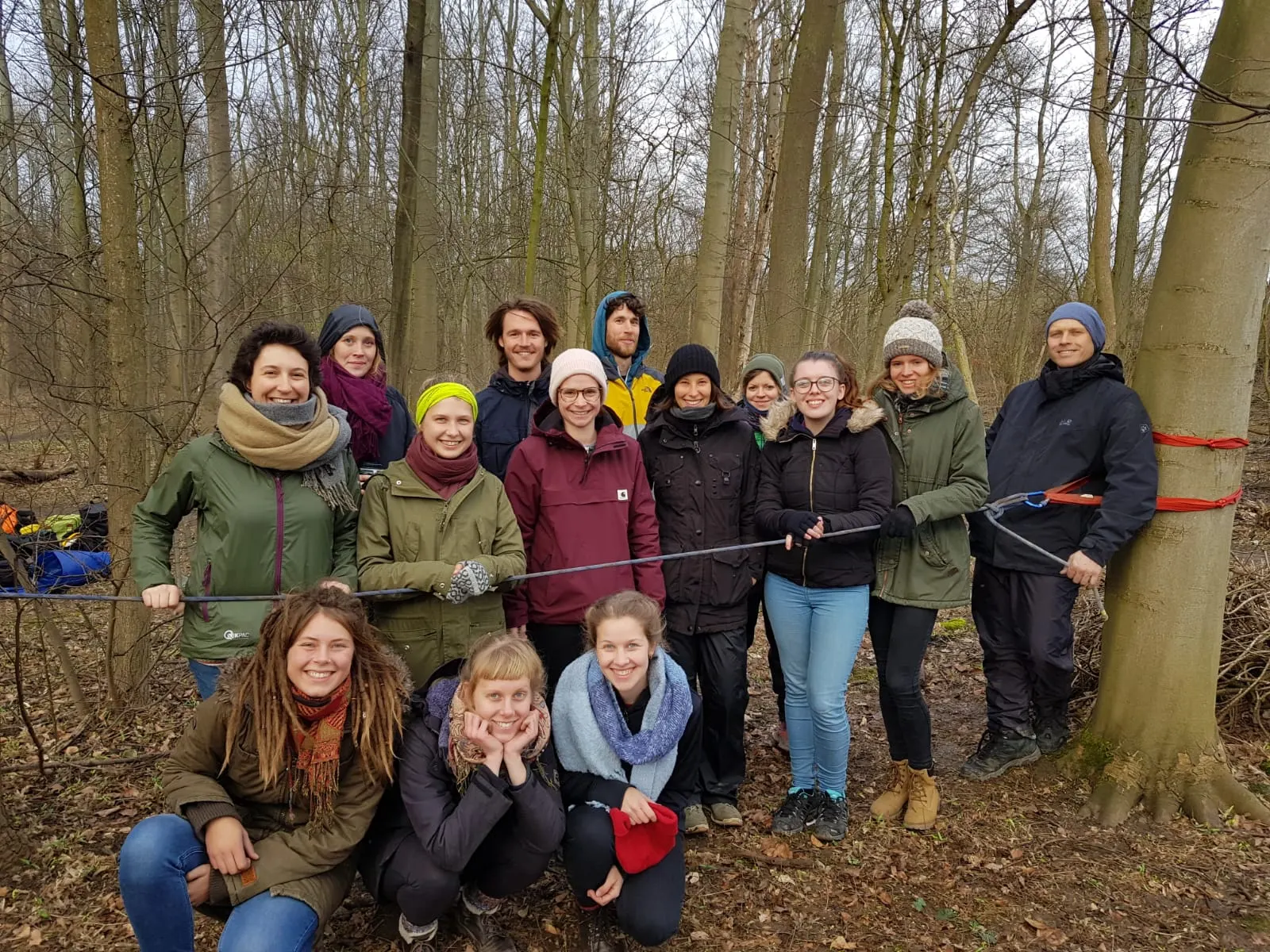 Gruppenfoto der neuen HochseilgartentrainerInnen im winterlichen Wald, vor ihnen ein zwischen zwei Bäumen gespanntes Sicherungsseil