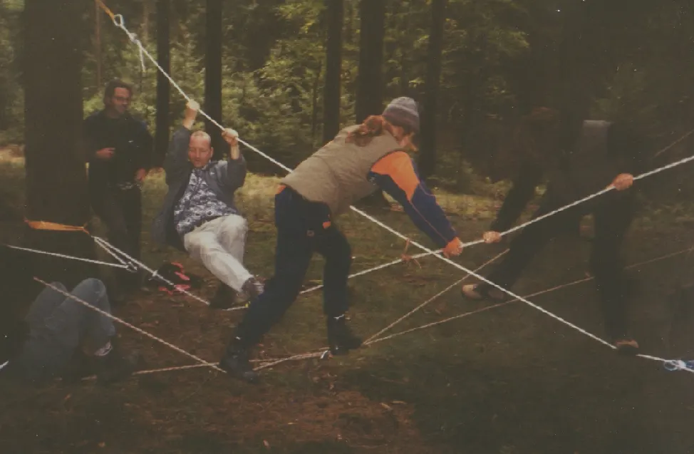 Älteres Foto: Mehrere Personen bewegen sich im Wald gemeinsam durch ein Netz aus gespannten Seilen