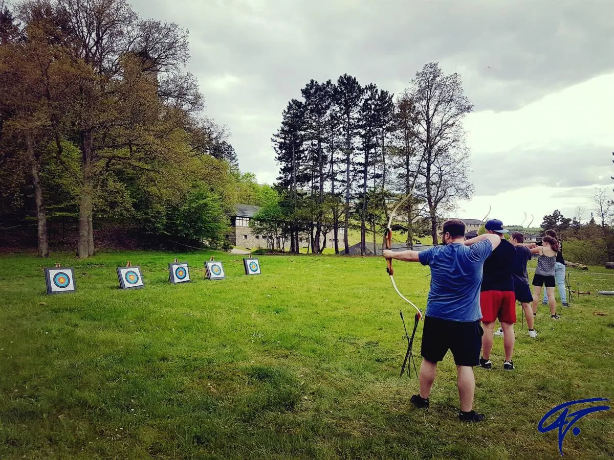 Eine Gruppe schießt auf einer großen Wiese mit Pfeil und Bogen auf eine Reihe von Zielscheiben