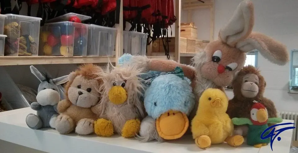 Eine Reihe Kuscheltiere sitzt vor Regalen mit Spielmaterial