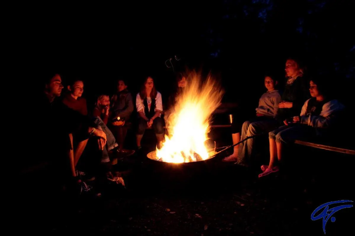 Eine Gruppe sitzt nachts um ein Lagerfeuer