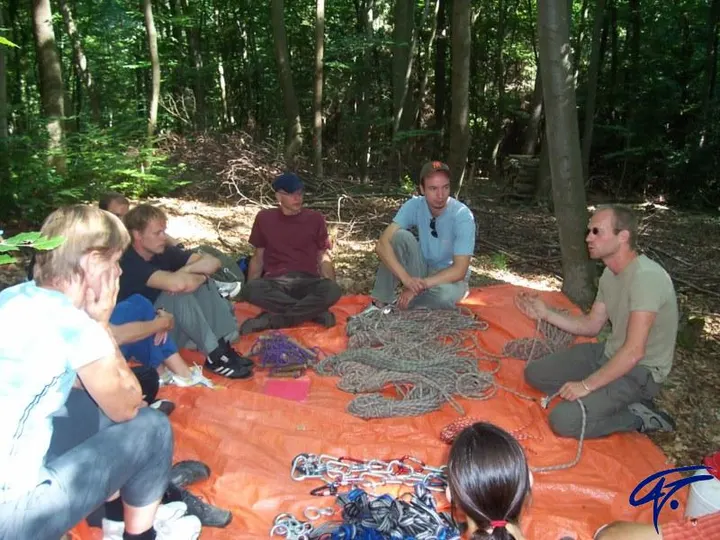 Eine Gruppe sitzt im Wald auf einer Plane voller Seile und übt Knoten